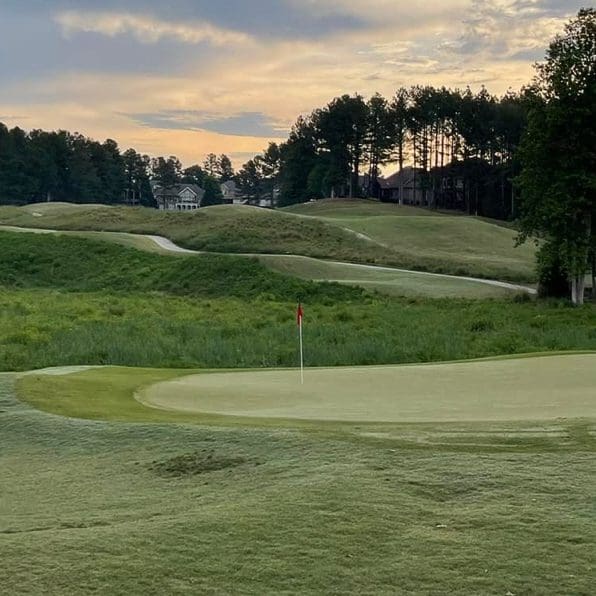 Golf course green with flag and sunset