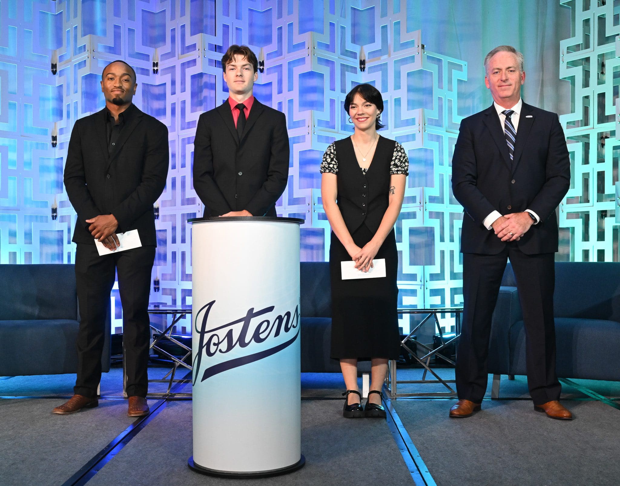 Four formally dressed people standing on stage